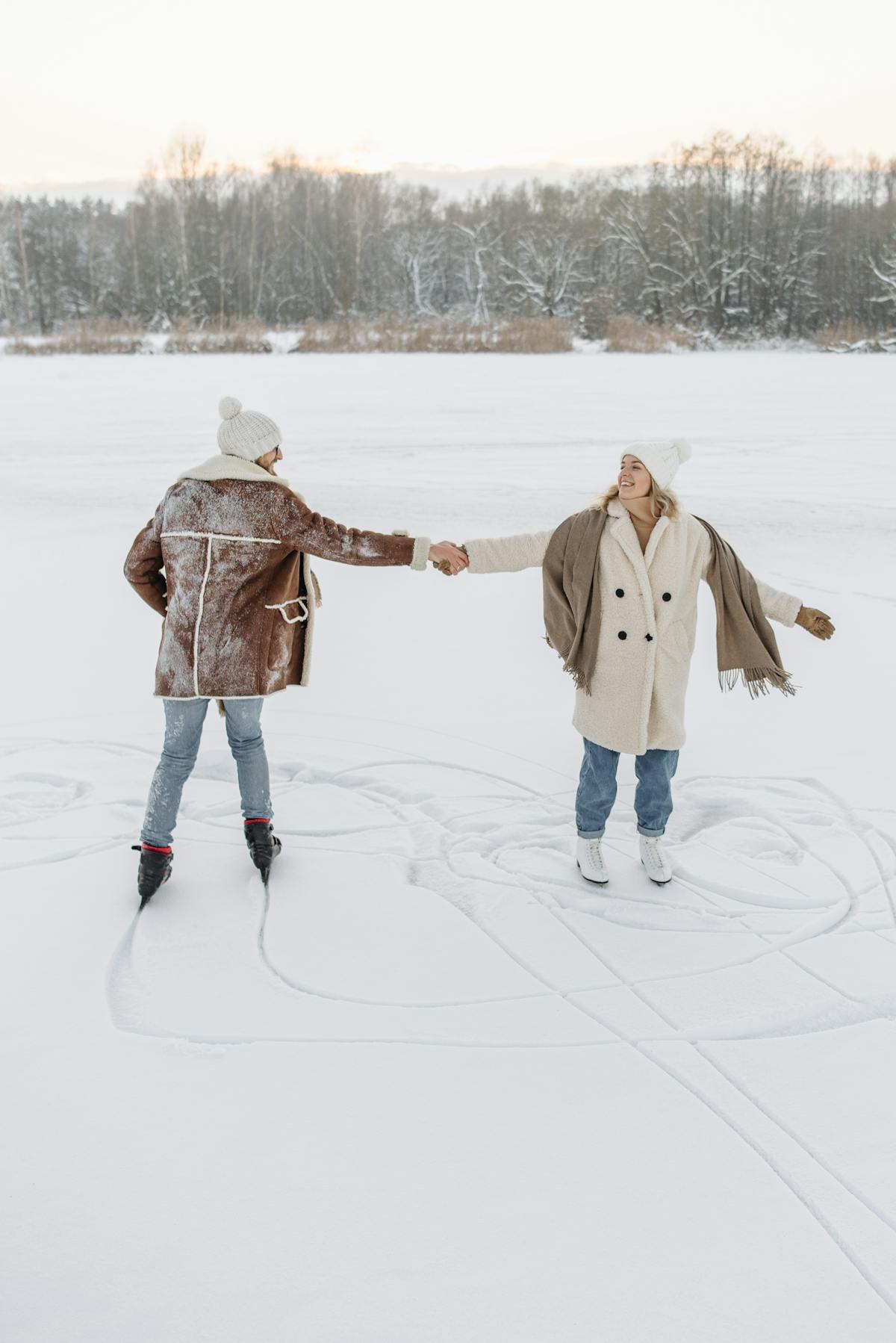 Couple holding hands while ice skating in winter